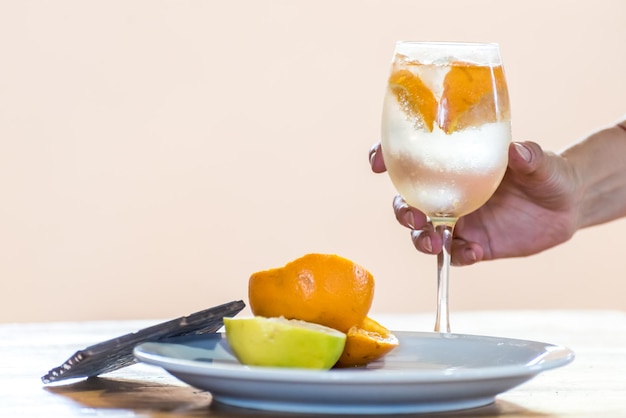 Человек, держащий стакан апельсинового сока и дольку апельсина на тарелке.