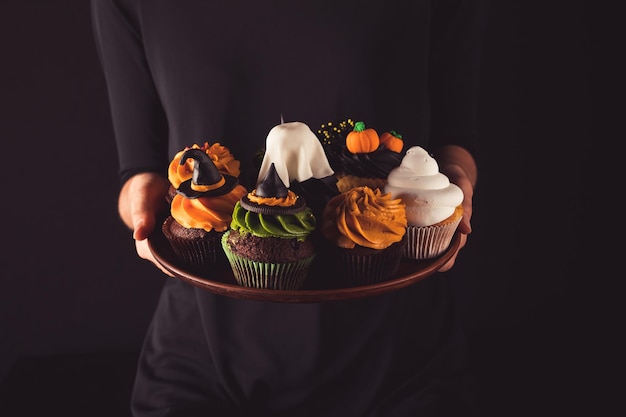 person holding halloween cupcakes