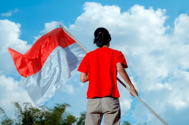 Foto una persona che tiene la bandiera nazionale indonesiana giorno dell'indipendenza indonesiano