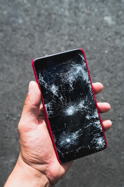 Foto persona in possesso di smartphone di grandi dimensioni con schermo rotto
