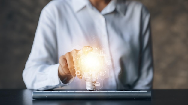 Person holding light bulb with earth hologram and renewable energy hologram globe and wind energy used as pure renewable energy to reduce high cost oil wind energy is natural energy Global warming