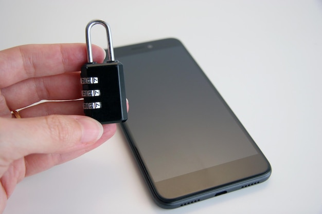 A person holding a lock that is next to a phone.