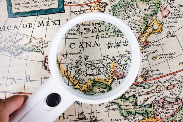 Photo a person holding magnifying glass over map