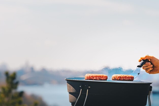 Foto persona che tiene la carne sulla griglia al barbecue contro il cielo