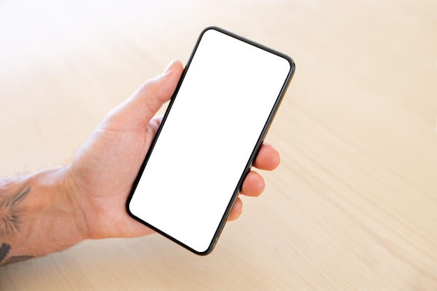 Person holding mobile phone in hand blank white screen\
mockup