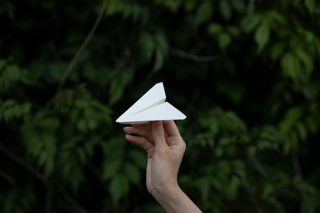 Person holding paper plane. taking flight. a woman\'s hand holds\
a paper airplane against a blurred b