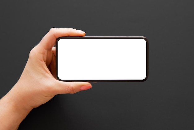 Person holding phone horizontally in one hand on dark\
background