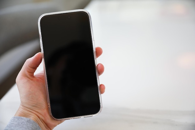 A person holding a phone with a blank screen.