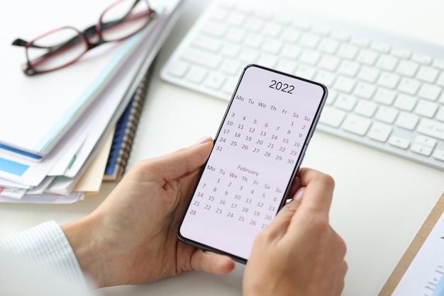 Photo person holding phone with calendar for 2022 closeup