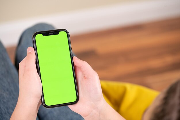 A person holding a phone with a green screen