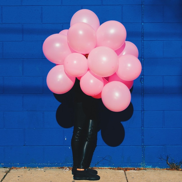 Photo person holding pink balloons in front of face