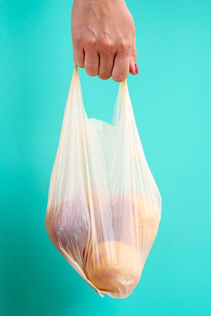 Person holding plastic bag with fruits 