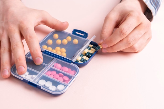 A person holding plastic medicine pill box and taking a tablet