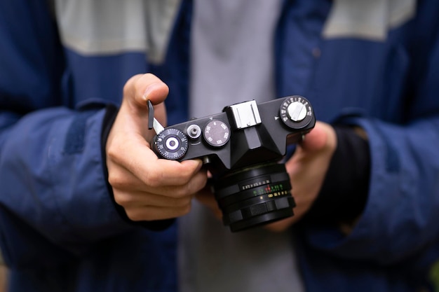 A person holding retro metal camera and adjusting settings