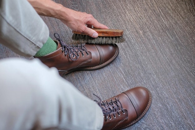 человек, держащий щетку для обуви и чистящий и чистящий пару обуви
