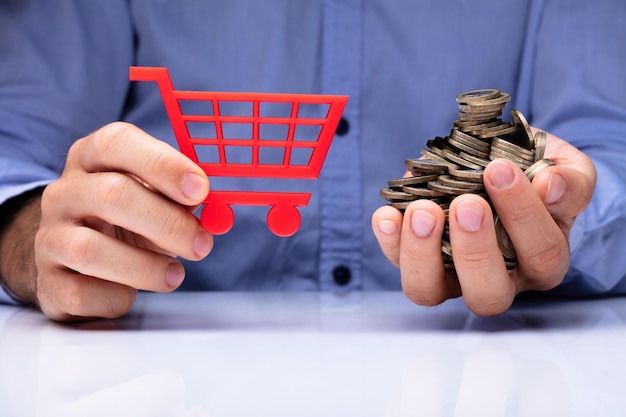 Person Holding Shopping Cart And Many Coins