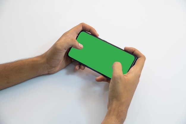 Person holding a smartphone with green screen