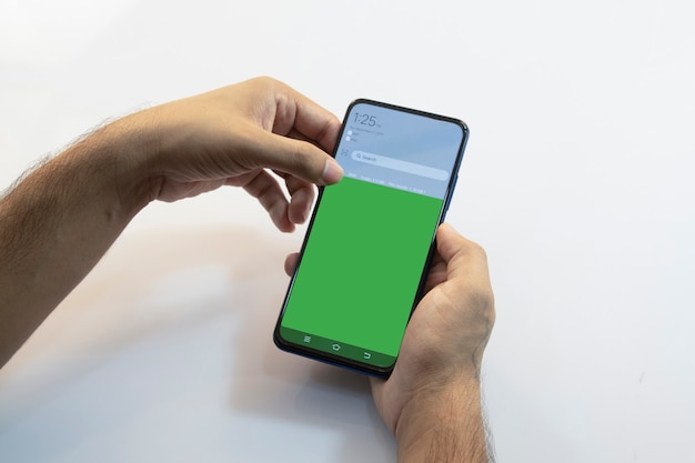 Person holding a smartphone with green screen