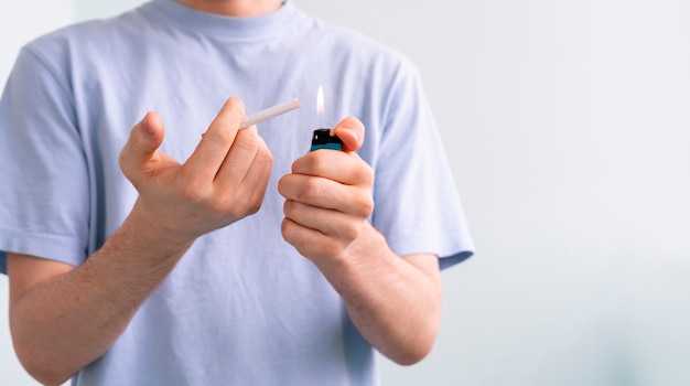 A person holding a spark lighter flame and a cigarette, smoking bad habbit