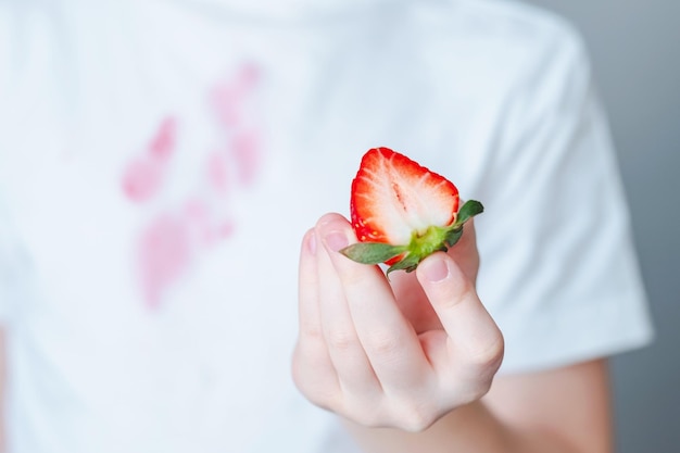 A person holding a strawberry in their hand Close up child's hand holding a sliced strawberry