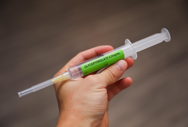 A person holding a syringe with a green label that says " natural ".