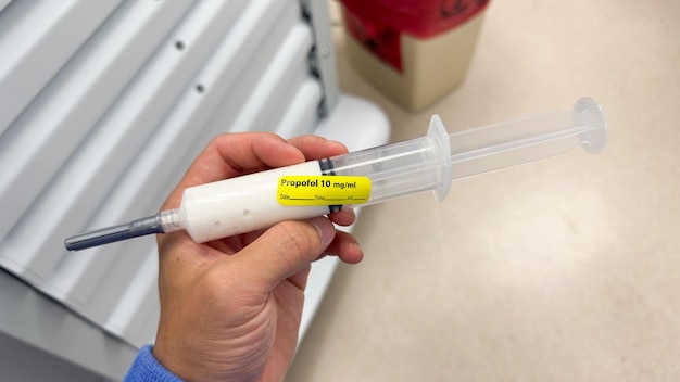 A person holding a syringe with a yellow label that says " proximal 19 acid ".