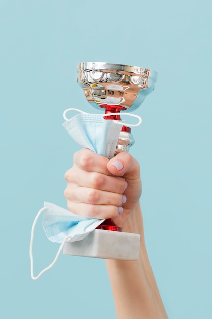 Photo person holding a trophy and a medical mask