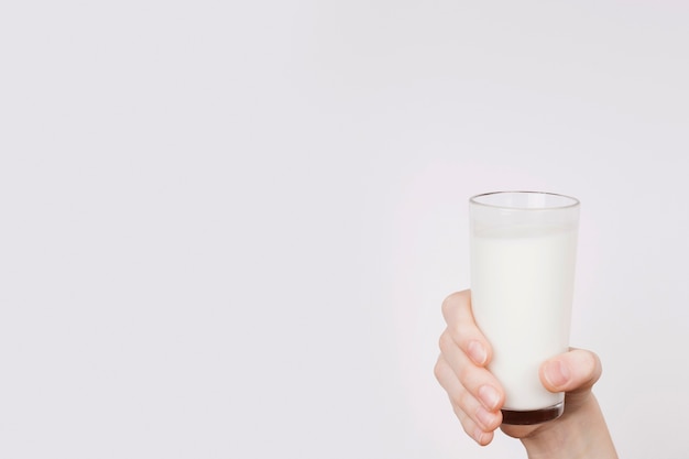 Photo person holding up a glass of milk with copy space