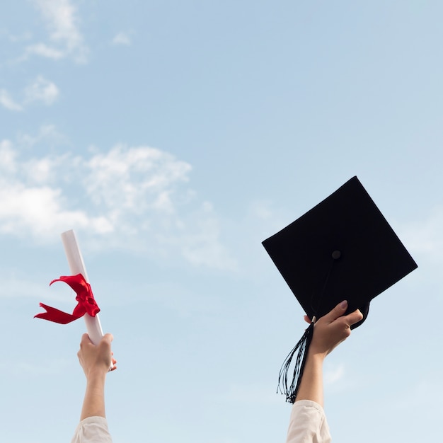 Photo person holding up graduation cap and diploma