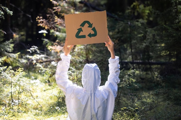 Foto una persona che regge un cartello di riciclo in una foresta