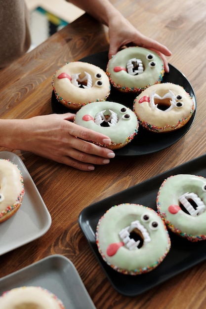 Photo person holding a vampire designed donuts on the table