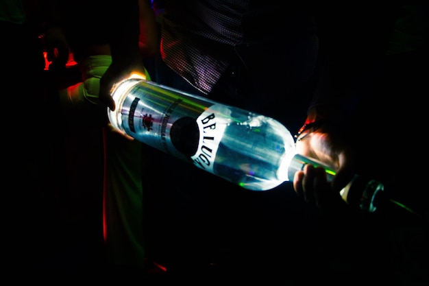 Person holding wine bottle in darkroom