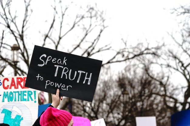 Photo person holding with text on placard in city during protest