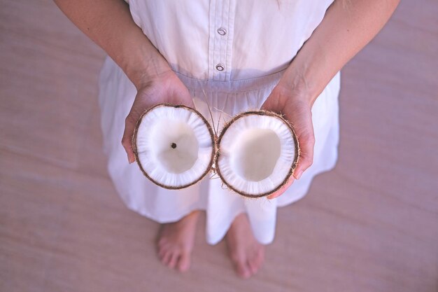 写真 人は女性の手で壊れた甘くてジューシーなココナッツの新鮮なココナッツの半分を保持しています。