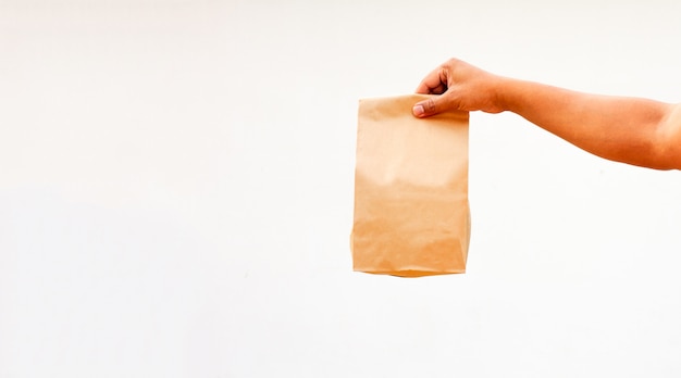 Person holds brown empty craft paper bag for takeaway