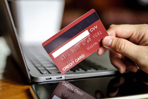 The person holds a credit card and is filling out their credit card information to pay for goods online, credit cards can pay for goods and services both in the storefront and online shopping.