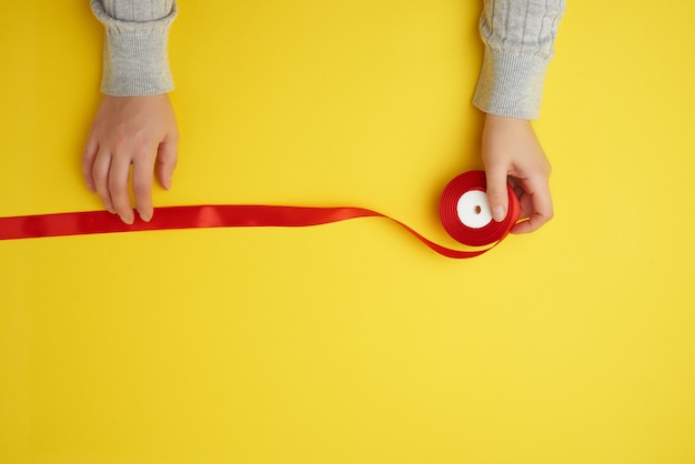 Photo person holds red ribbon on a yellow surface