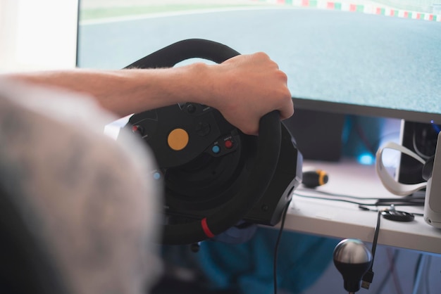 A person improving his driving skills race simulator with steering wheel and pedals