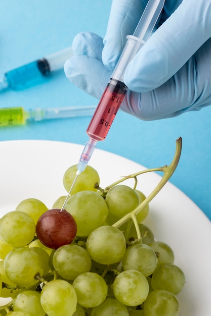 Person injecting grapes on plate close-up