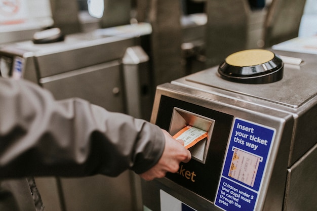 person inserting a ticket into a train station turnstile