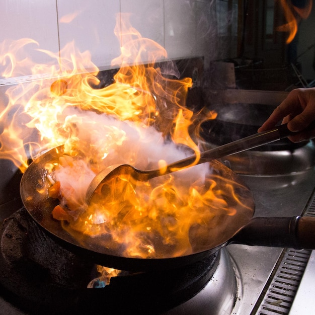 A person is cooking in a kitchen with a fire in the air.