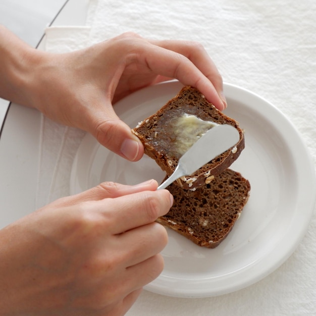 a person is eating a sandwich with butter on it
