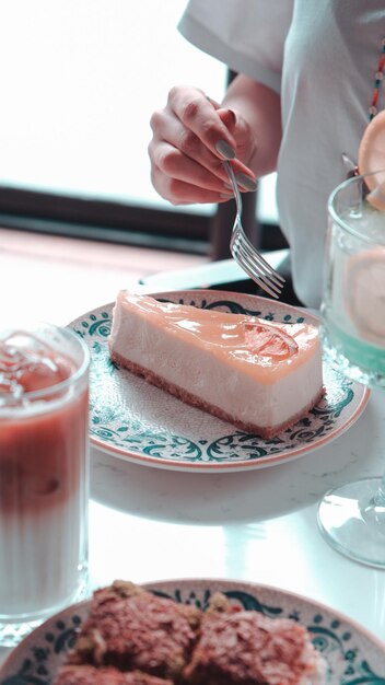 a person is eating a slice of cake and a drink