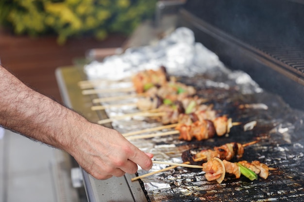 A person is grilling skewers with skewers of food on the grill.