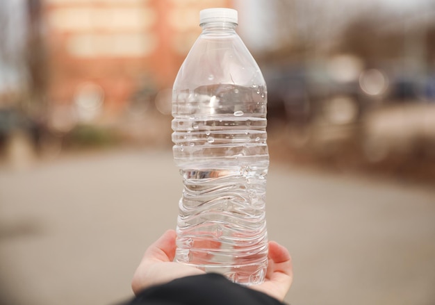 手に水の入ったボトルを持っている人。