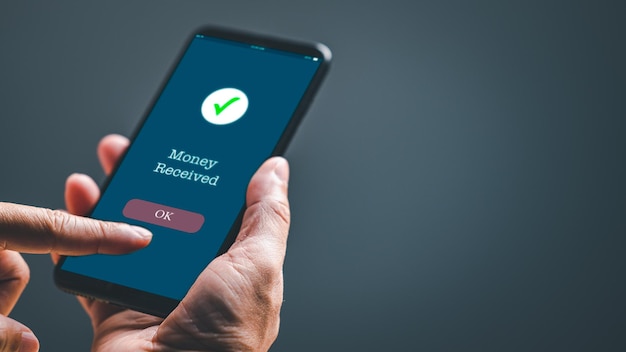 A person is holding a cell phone that says Money Received on it