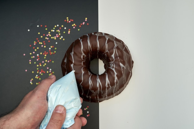 Photo a person is holding a chocolate covered donut that is covered in white frosting.