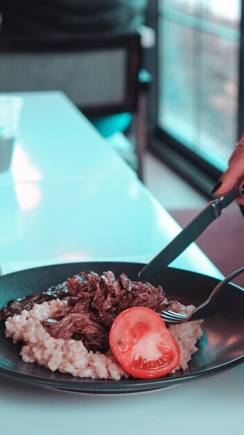 a person is holding a fork and a bowl of food with a knife and fork