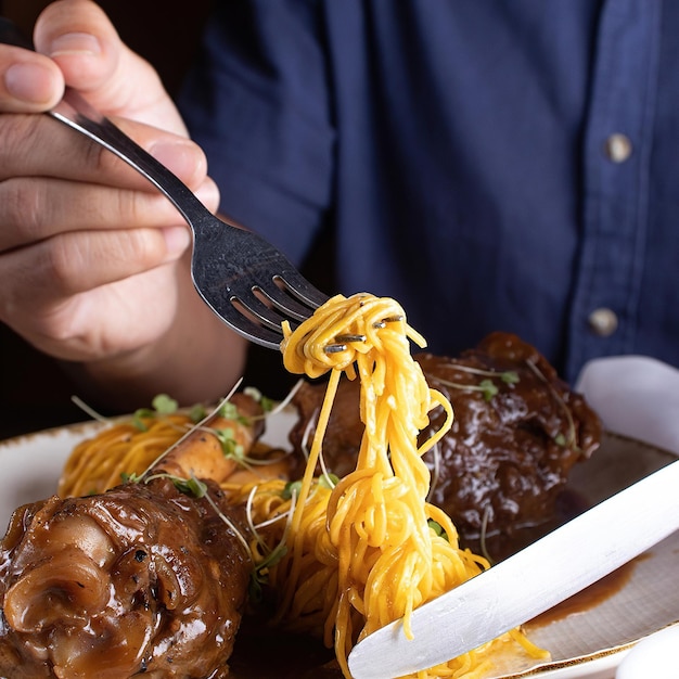 A person is holding a fork with noodles on it.
