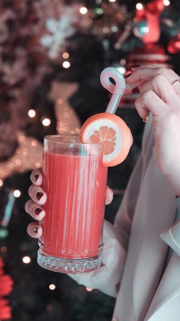 a person is holding a glass with a lemon and a slice of orange